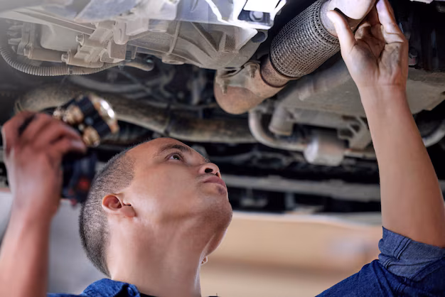 Mechanic inspecting car exhaust for potential faults